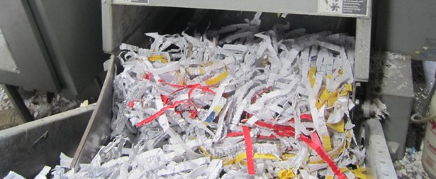 A pile of shredded paper in front of a machine.